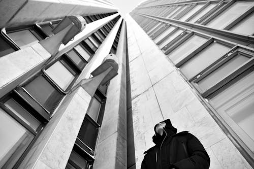 Free Low Angle Shot of Man in Black Jacket standing beside High-rise Buildings  Stock Photo