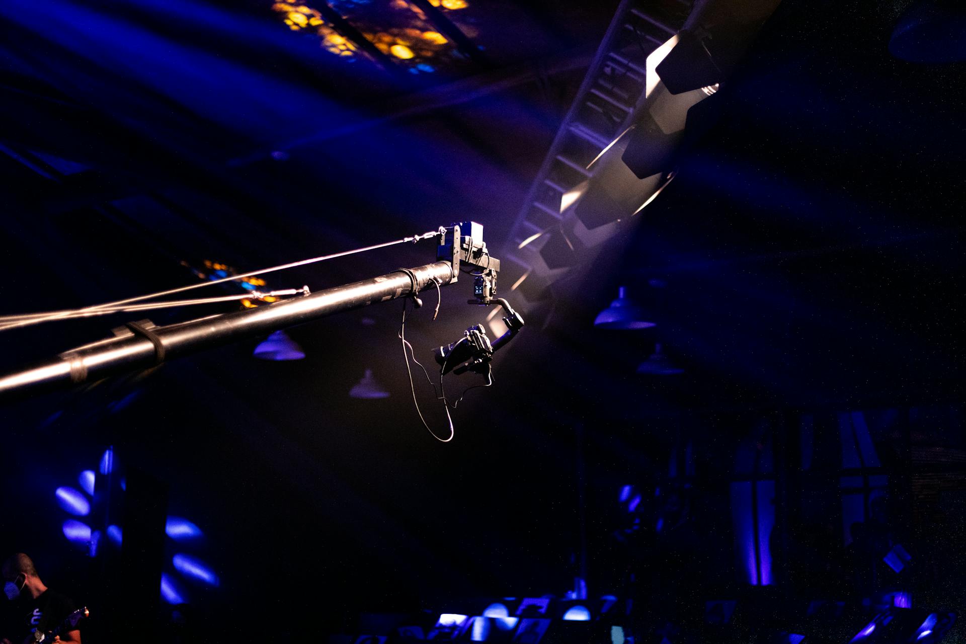 Camera crane setup at a concert venue with dramatic lighting and vivid colors.