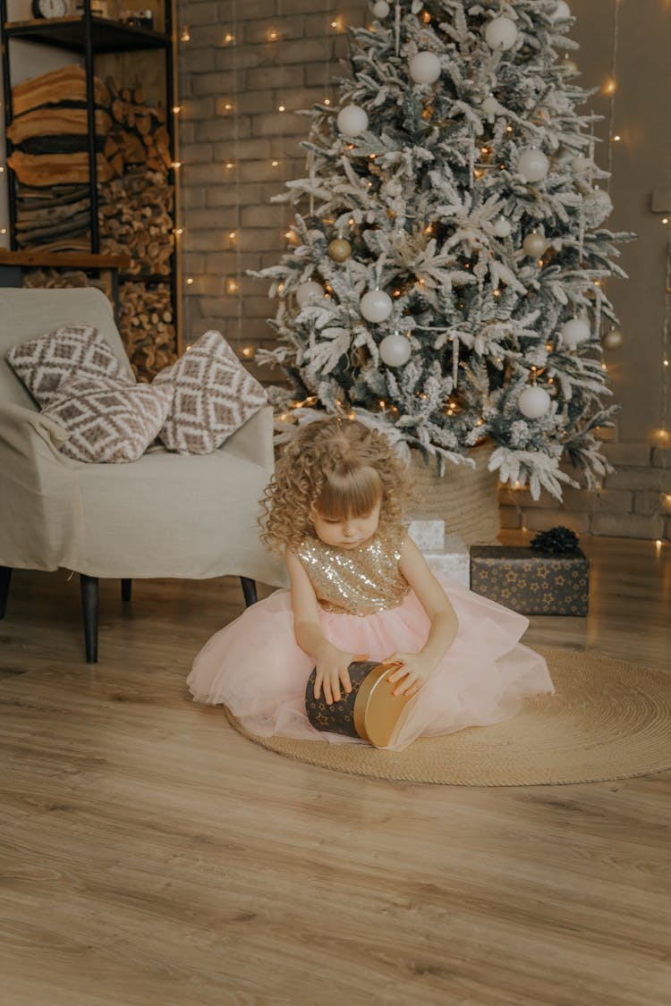 Girl Opening Gift Near Christmas Tree