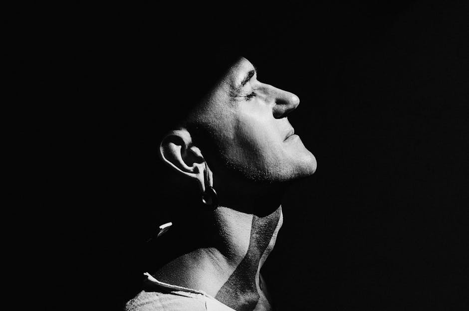 A powerful side profile portrait of a man in dramatic black and white lighting.