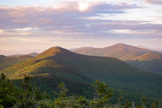 Explore the serene beauty of Vermont's green mountains during sunrise, capturing nature's peaceful essence.