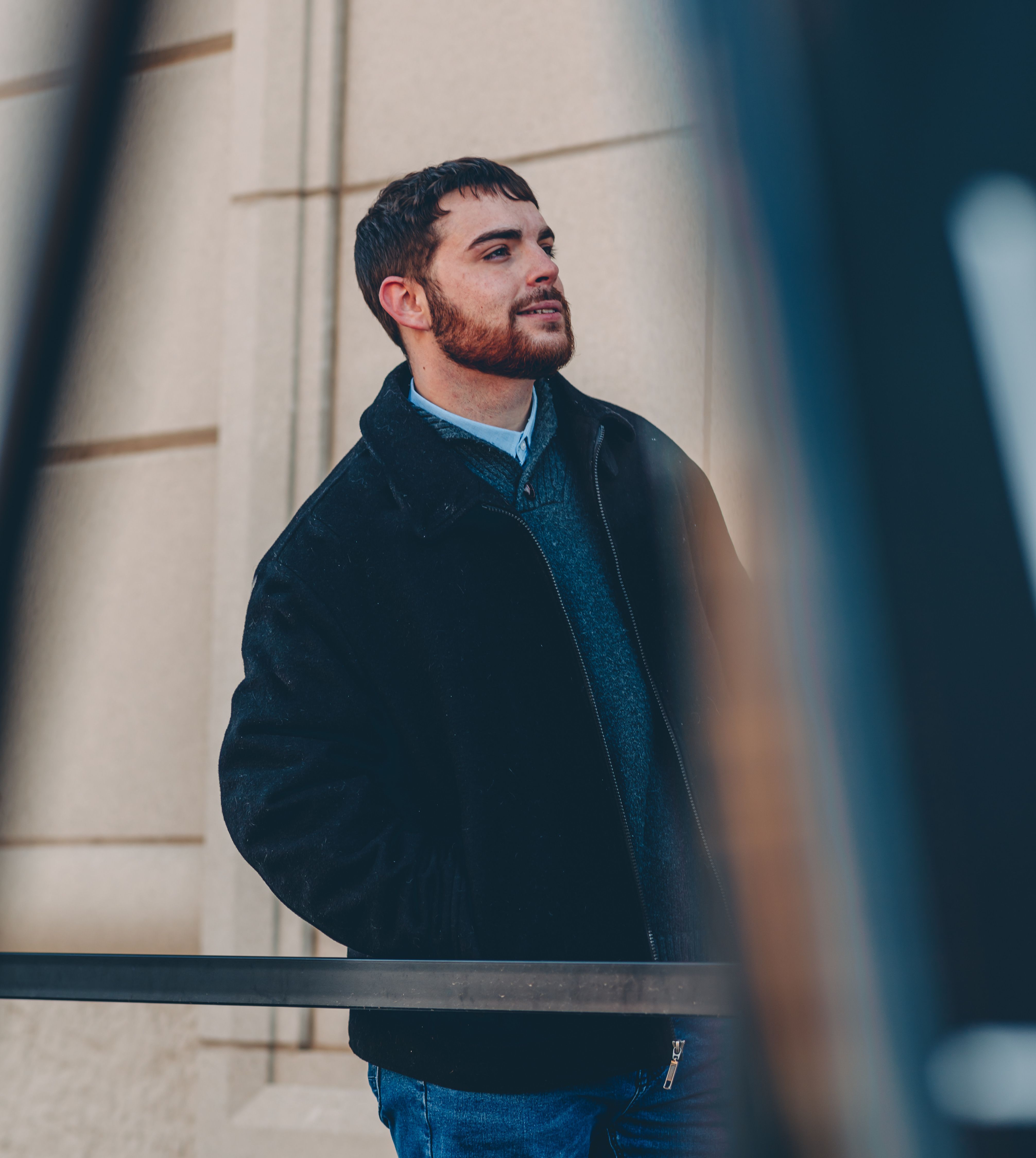 A man confidently posing outdoors in warm autumn fashion, showcasing modern style and elegance.