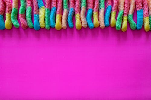 Top View of Rainbow Color Sweets on Pink Background 