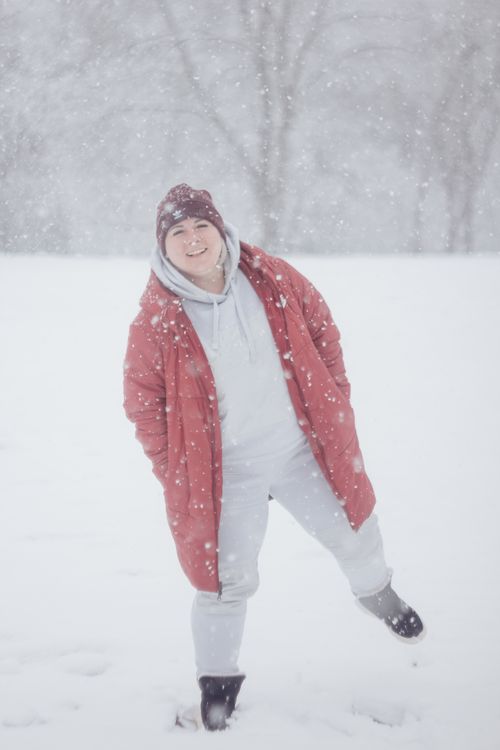 Free Happy woman in a red coat smiling while enjoying a snowy winter day outdoors. Stock Photo