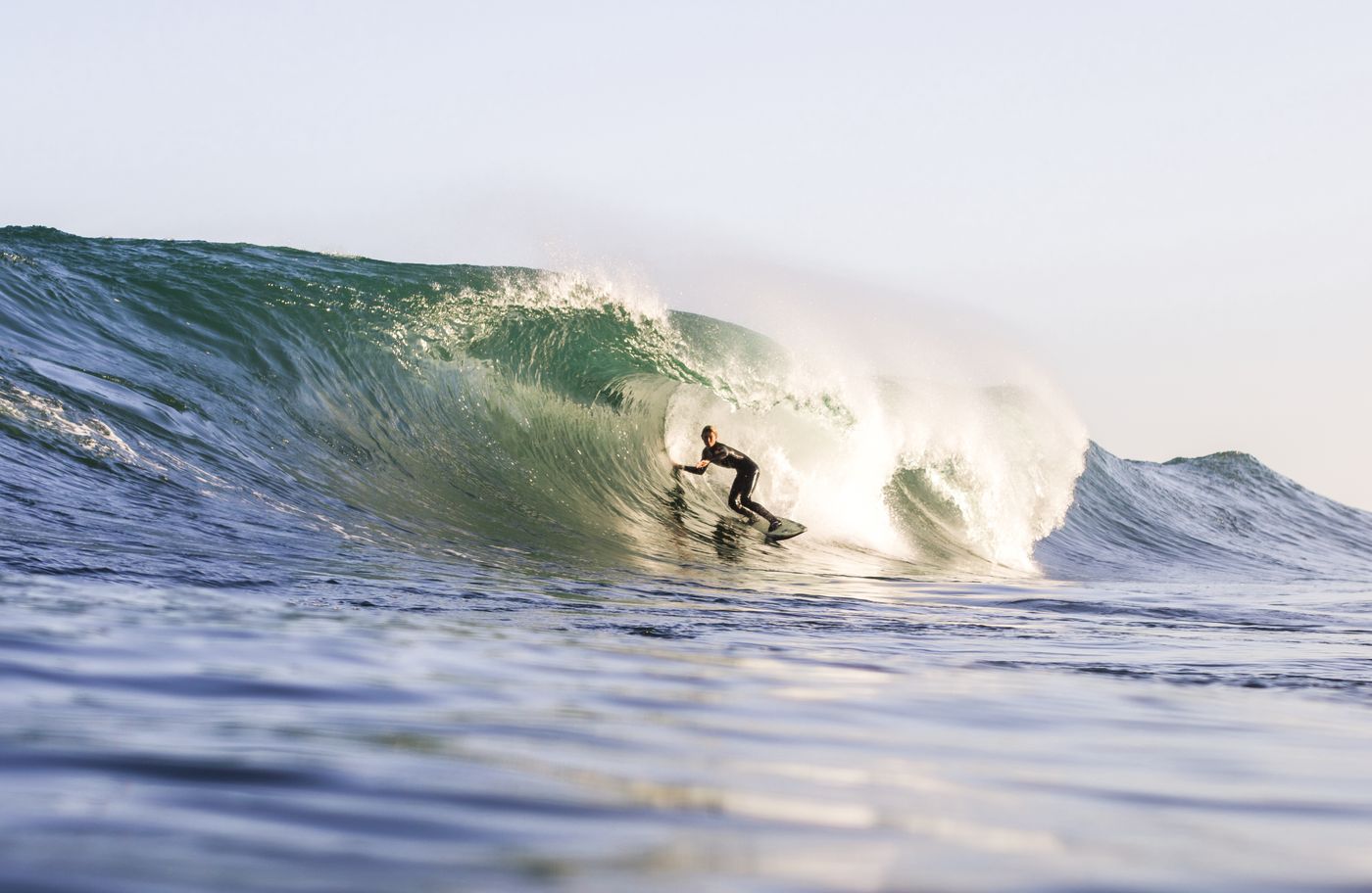 Surfer riding an ocean wave in bright coastal conditions