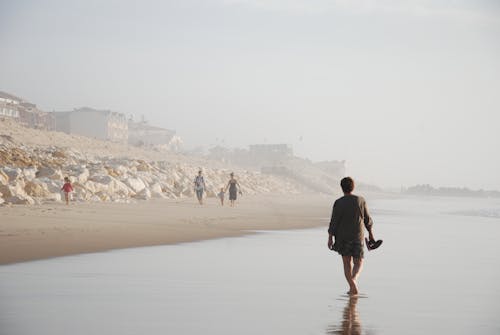 People Walking on Beach on a Foggy Day