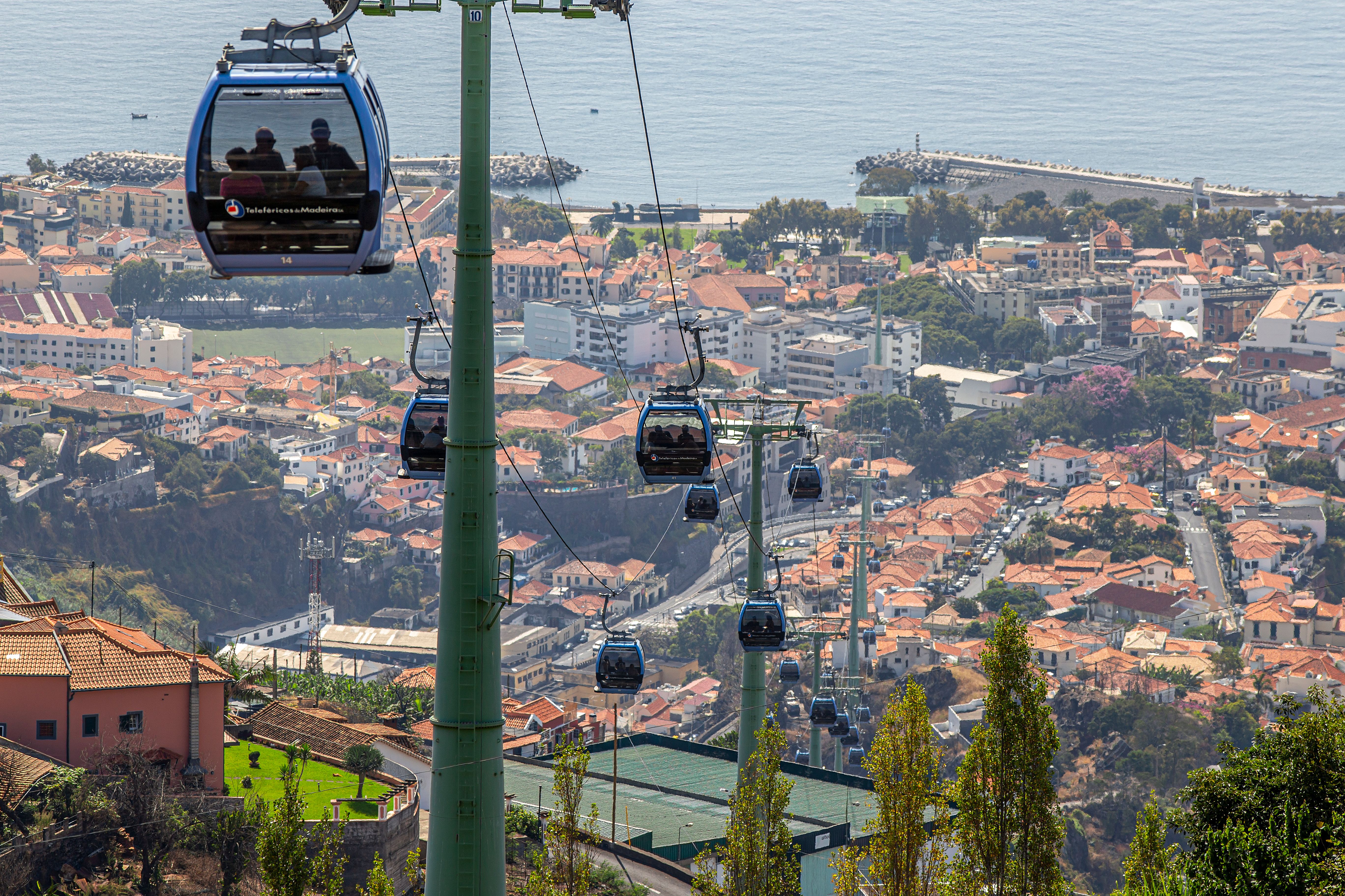 Eine malerische Ansicht von Seilbahnen über Funchal, Madeira, mit dem Ozean im Hintergrund.