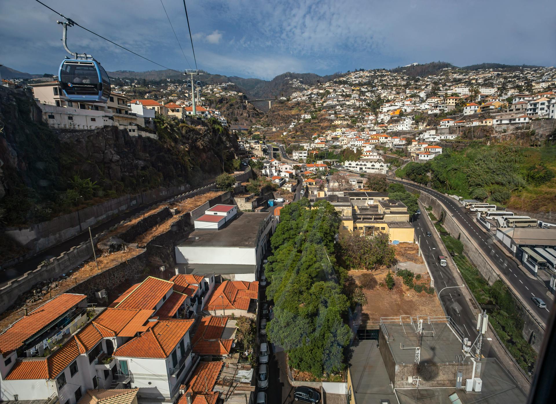 Aerial shot of Madeira Island showcasing town, cliffs, and cable car.