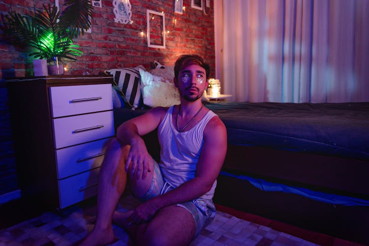 A Man In White Tank Top Sitting On The Floor