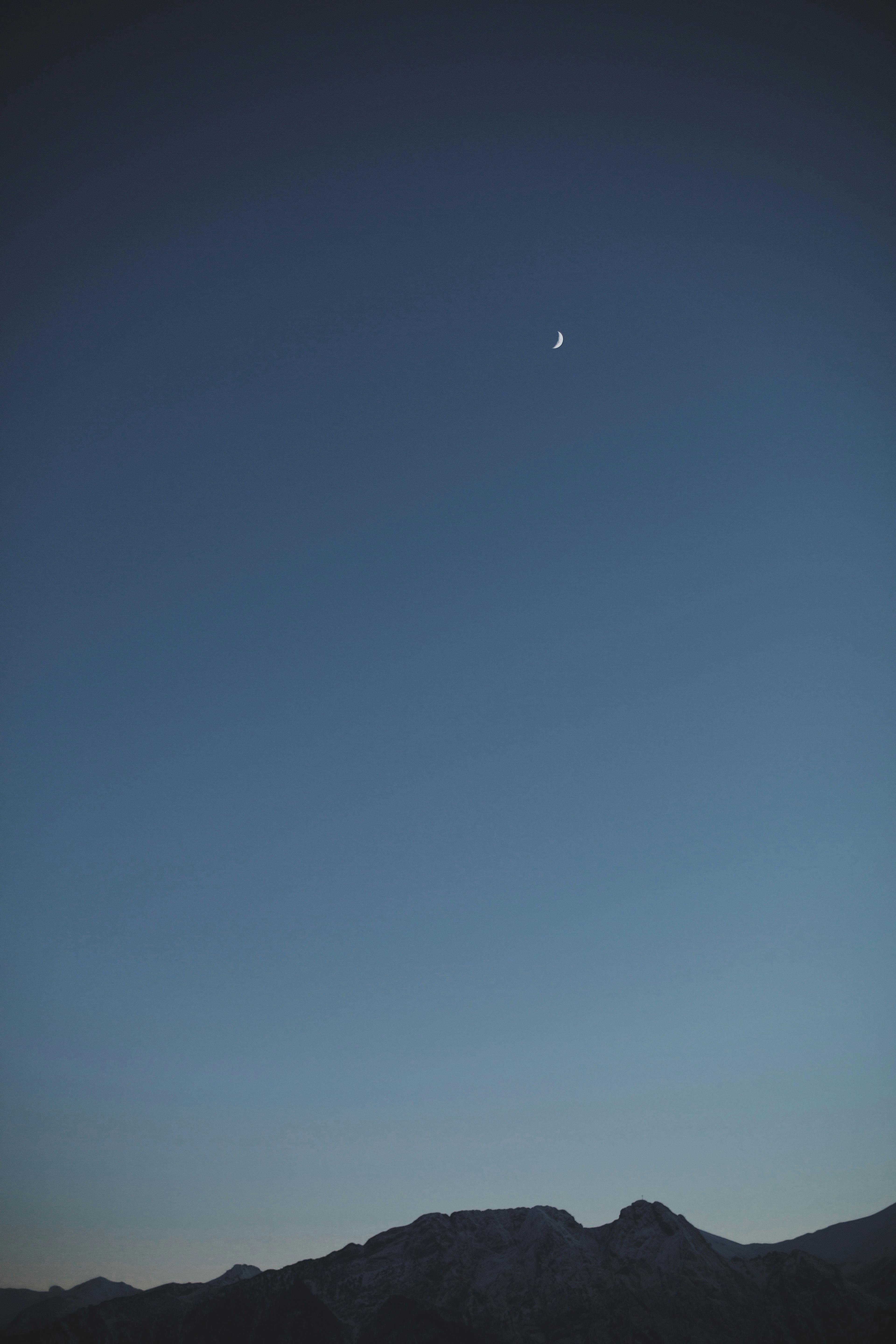 Serene night sky with crescent moon above the Vysoké Tatry mountains in Slovakia.