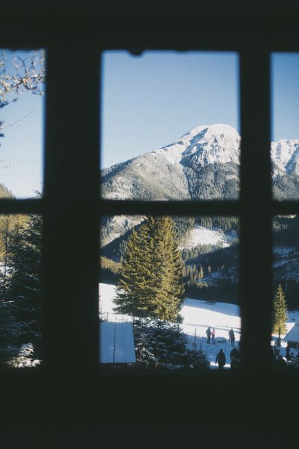 Scenic winter landscape of Vysoké Tatry, Slovakia, seen through a window, capturing snowy mountains and pine trees.