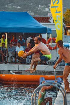 Energetic water polo game with a packed audience, showcasing a player mid-air holding the ball