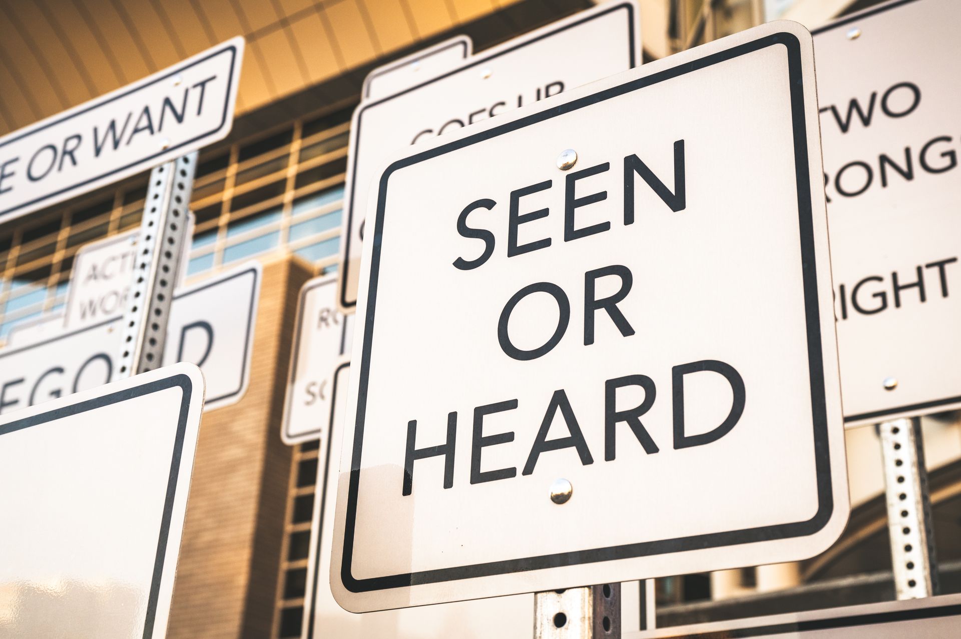 Creative street signs with thought-provoking messages and wordplay in an urban setting.