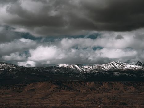 Captivating view of snow-capped mountains beneath dark clouds in Cortez, Colorado.