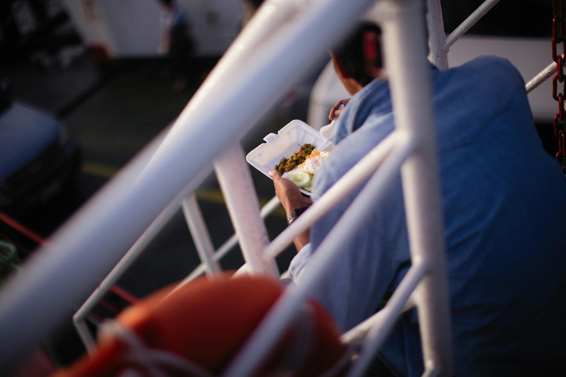 Man enjoying a meal on a ferry deck, capturing a serene moment at sea.