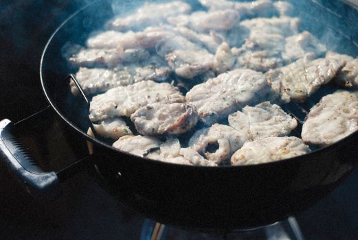 Close-up of fish fillets sizzling on a barbecue grill outdoors, exuding a smoky aroma.