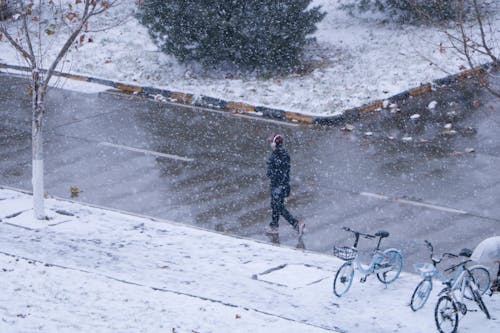 

A Person Walking on a Road during a Snowy Day