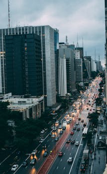 城市大道上，摩天大楼林立，夜间交通繁忙，呈现出一片热闹的城市场景