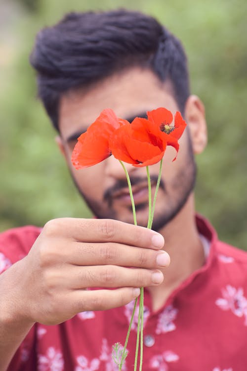 Close Up Photo of a Man Holding Red Flowers