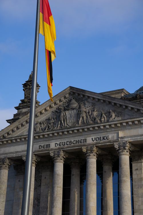 Free The historic Reichstag in Berlin with a waving German flag under a clear sky. Stock Photo