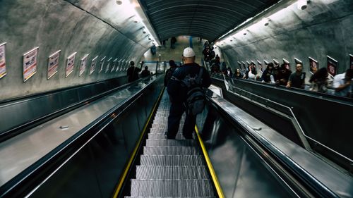 Free A crowded subway station escalator filled with diverse commuters descending. Stock Photo
