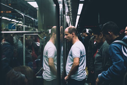 Man in Gray and Black Stripes Shirt in Train Station Looking Towards Train Door