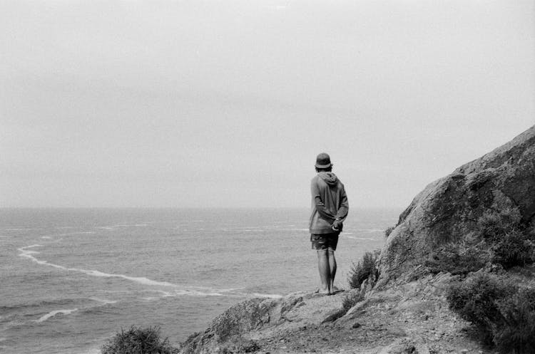 Man Standing On A Cliff And Looking At The Sea 