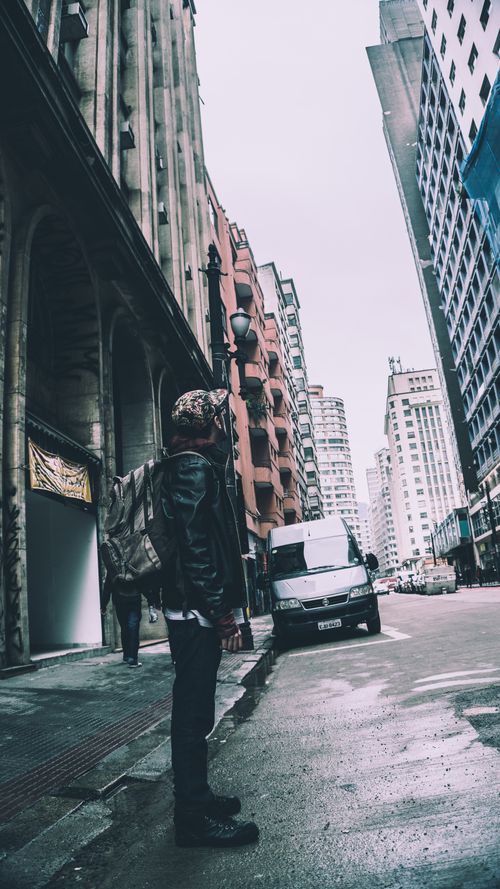 Free Man stands on the street surrounded by tall buildings in a bustling city. Stock Photo