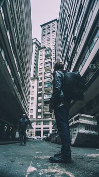 Backpacker in an urban alley, surrounded by towering skyscrapers, highlighting the modern city atmosphere.