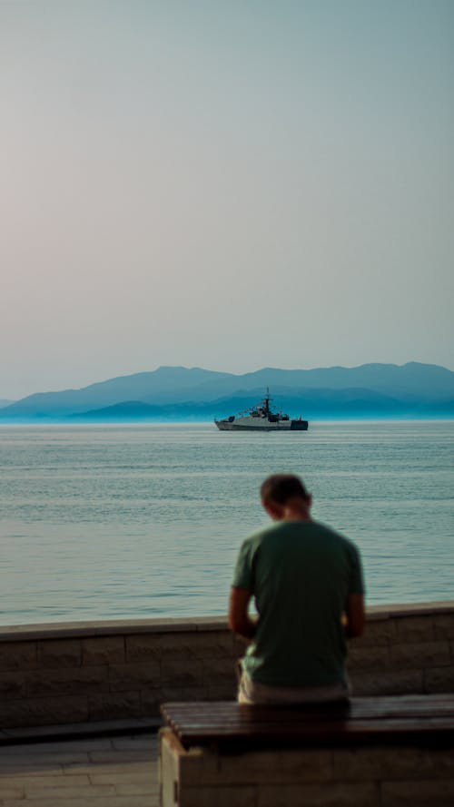 A Person Sitting on a Wooden Bench on the Seaside