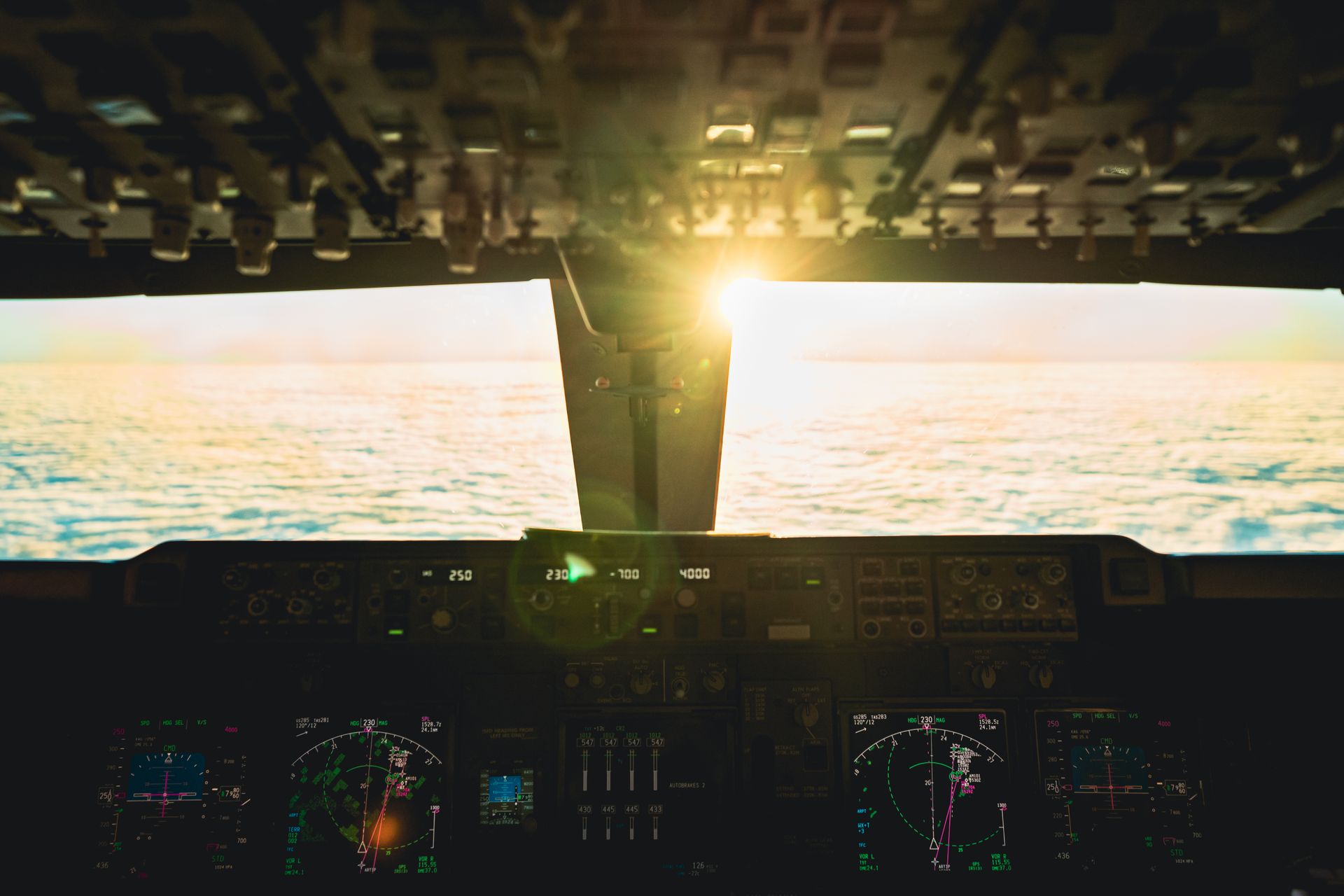 Captivating view from airplane cockpit at sunset over ocean, revealing flight controls.