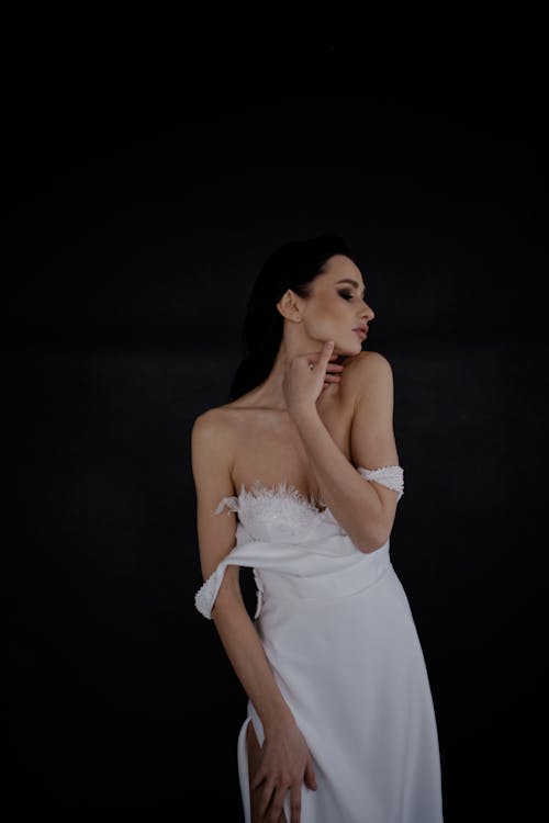 Free Portrait of Woman in White Dress Against Black Background Stock Photo