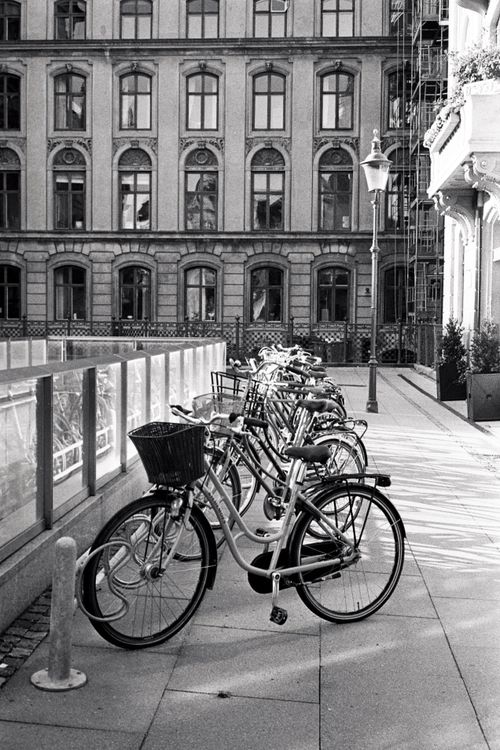 Free Black-and-white photo of bicycles parked on a Copenhagen sidewalk. Stock Photo