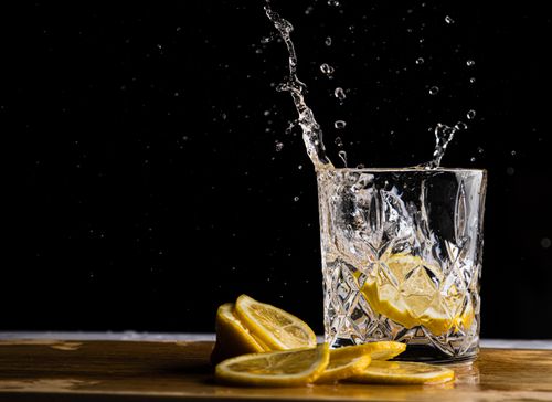 Free Close-up shot of lemon slices splashing in a crystal glass with a dark background. Stock Photo