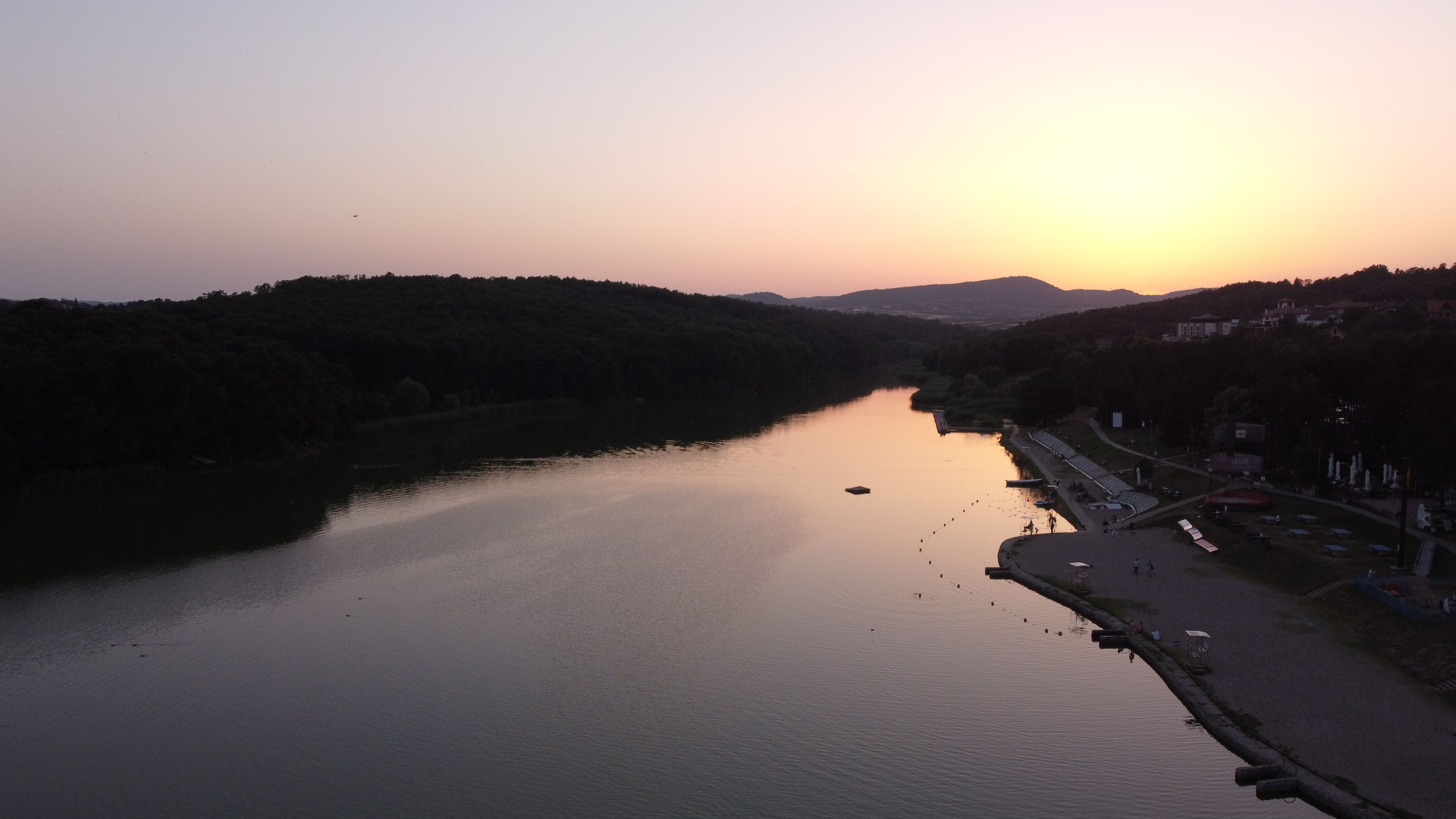 A tranquil river scene in Serbia at sunset with hills and reflections.