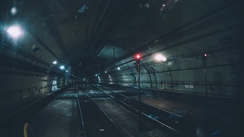 Free Moody image of a dimly lit urban subway tunnel with train tracks extending into the distance. Stock Photo