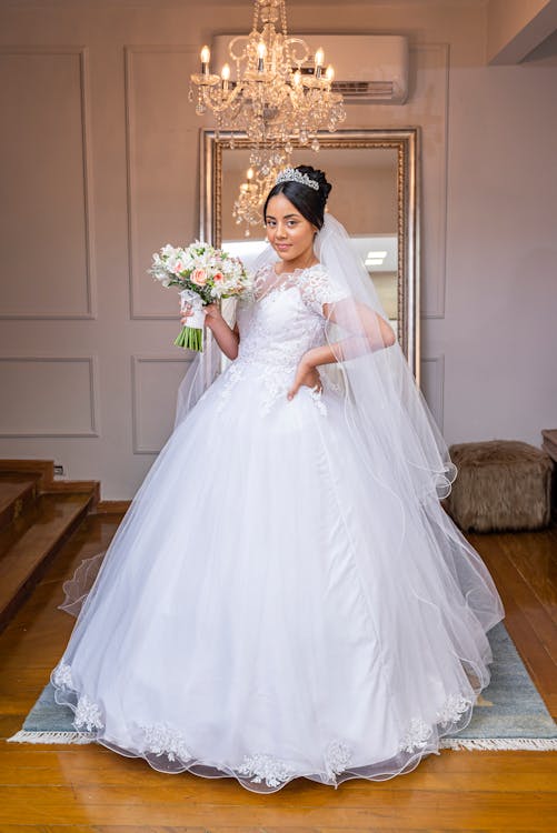 Free A Woman in White Wedding Dress Holding a Bouquet of Flowers Stock Photo