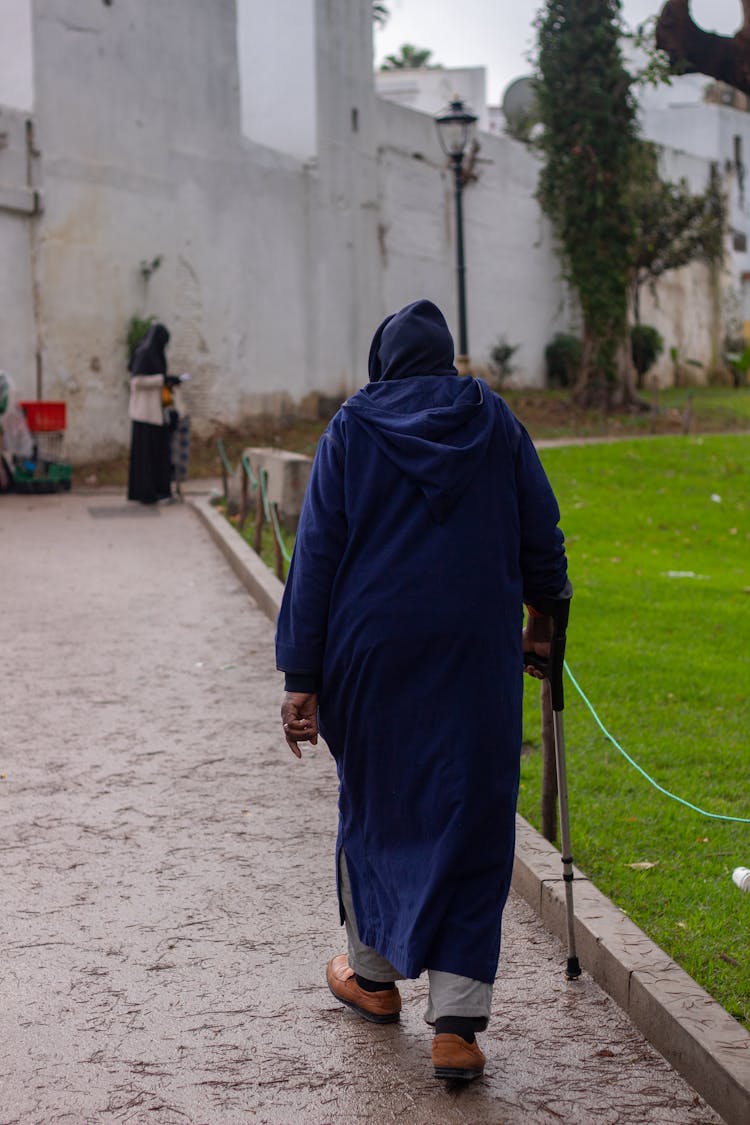 Man Wearing Djellaba Walking With A Crutch 