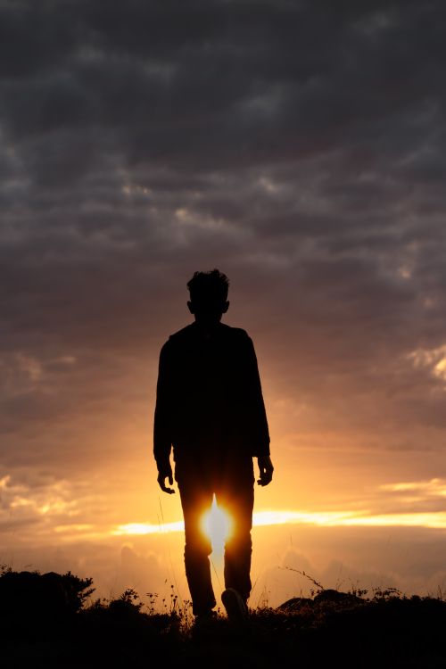 Free A man silhouetted against a vibrant sunset in Turkey, creating a dramatic and serene scene. Stock Photo
