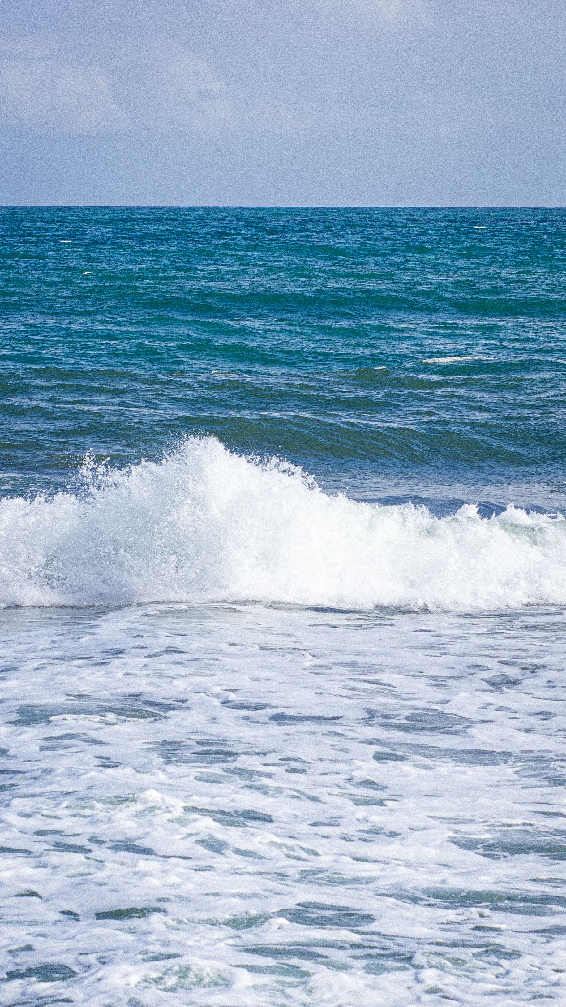Dynamic ocean waves crashing against the shore in Magdalena, Colombia on a sunny day.