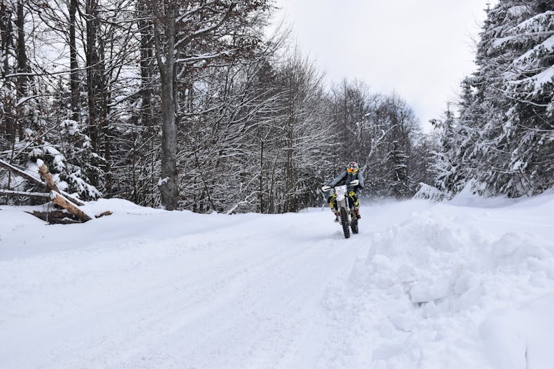 Motard sur une route forestière enneigée à Băiuț, Roumanie