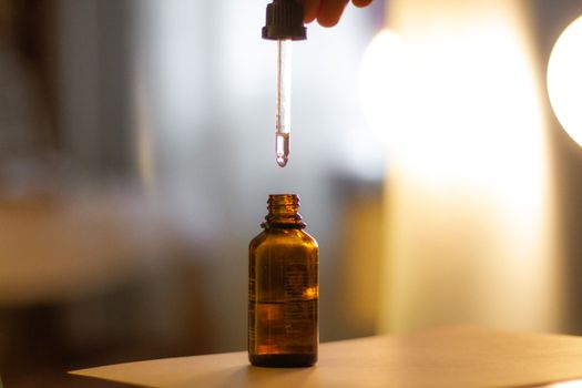 Close-up shot of a serum dropper above an amber bottle, with a soft blurred background and glowing light.