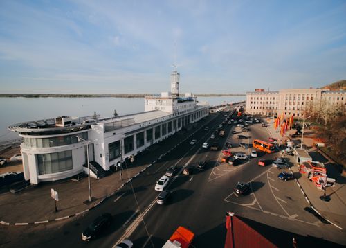 Free Aerial shot of a vibrant riverside street lined with historic buildings and vehicles, showcasing bustling city life. Stock Photo