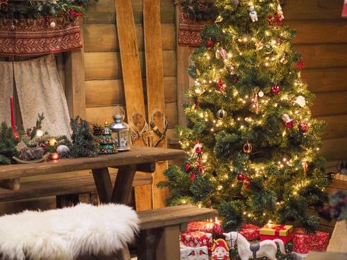 Free Warm indoor scene featuring a Christmas tree adorned with twinkling lights and rustic decorations in a cabin setting. Stock Photo