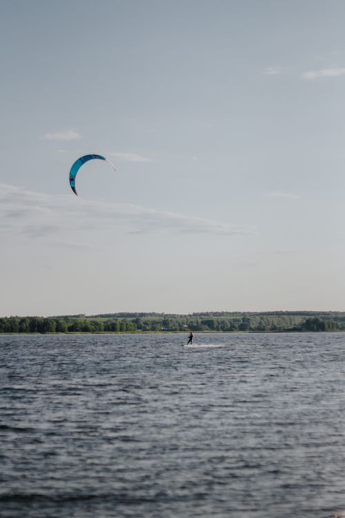 Free A lone kite surfer enjoying a thrilling ride over the ocean under a clear blue sky. Stock Photo