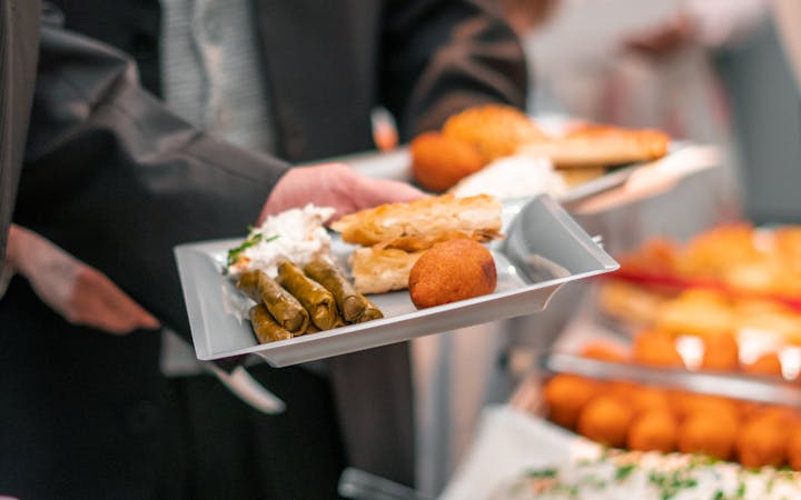 A business event with adults enjoying a diverse buffet featuring bread, pastries, and salads.