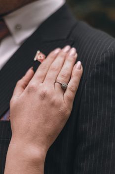 A close-up shot of a hand with an engagement ring resting on a pinstripe suit, symbolizing love and commitment.