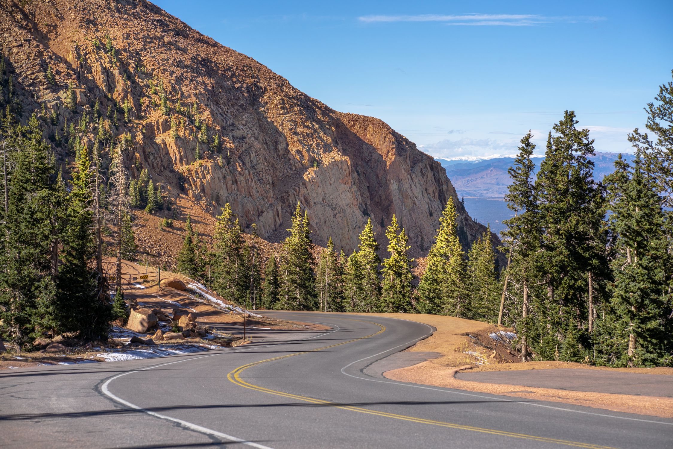 Winding road through scenic mountains and pine trees in Colorado.