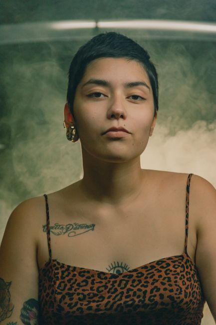 Moody portrait of a tattooed woman with short hair and leopard print dress.