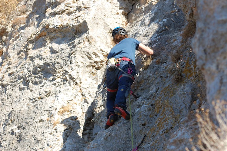 Low-Angle Shot Of A Woman Climbing A Rocky Mountain